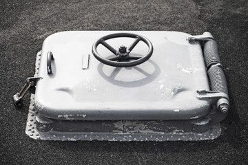 Old gray locked hatch on black ship deck