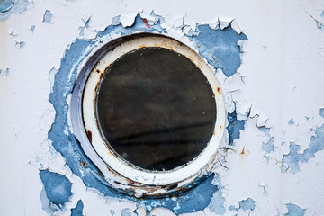 Round porthole in white and blue ship wall