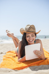 beautiful woman on the seaside lying on a beach towel to use a d