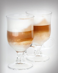 Two glass mugs with handles of latte coffee, macro photo
