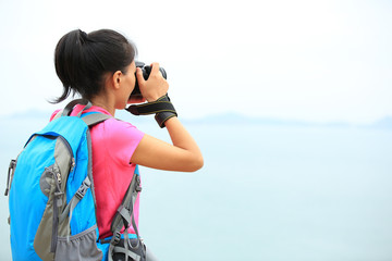 woman hiker taking photo seaside