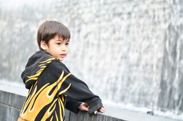 Little boy looking at waterfall fountain