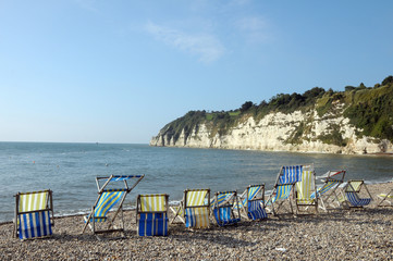 Fototapeta na wymiar Deckchairs on beach at Beer in South Devon