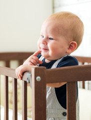 Baby boy is standing in the crib