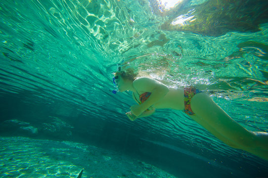 Young woman snorkeling in crystal clear laguna water on tropical