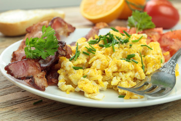 Hot scrambled eggs with chive, bacon and tomatoes for breakfast