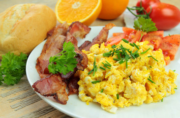 Breakfast with scrambled eggs with chive, bacon and tomatoes