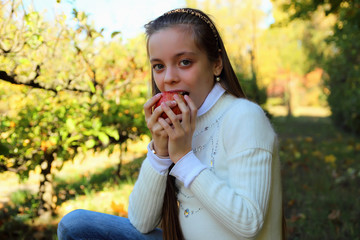 Cute little girl biting a ripe apple.