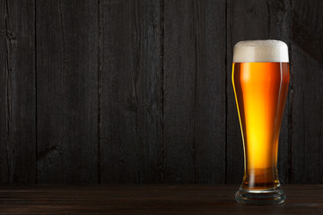 Glass of beer on wooden table, dark background