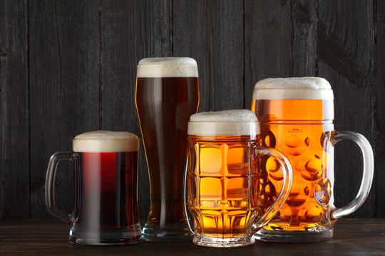 Beer glasses with various beer on table, dark wooden background