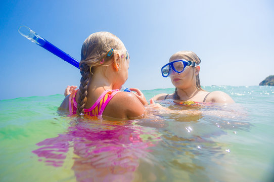 Mother teaching daughter snorkelling near beach on tropical isla
