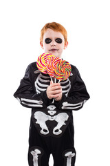 Happy young boy with skeleton costume holding colorful candies