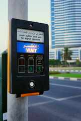 Button on the pedestrian crosswalk in Sharjah with blurred build