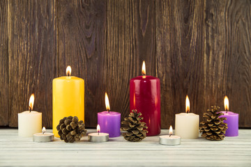 Obraz na płótnie Canvas fir-tree cones and candles on a wooden background