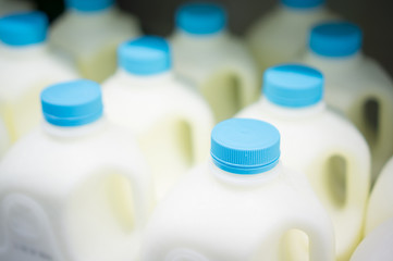 Bunch of milk bottles on fridge shelf in supermarket