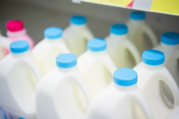 Bunch of milk bottles on fridge shelf in supermarket
