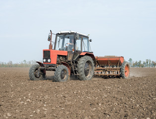 Obraz premium tractor and seeder planting crops on a field