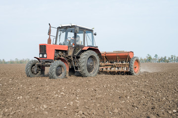 Obraz premium tractor and seeder planting crops on a field