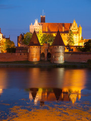 Obraz premium Malbork castle by night with reflection in Nogat river