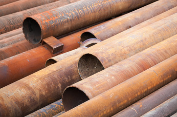 Rusted industrial steel pipes lay on the ground