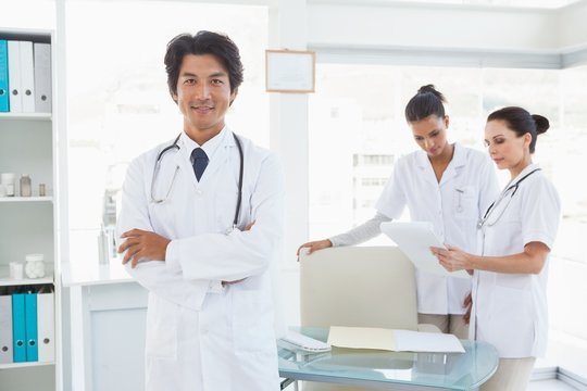 Doctor smiling in front of work colleagues