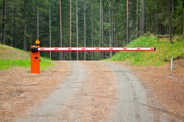 Rural road in the forest with closed red white barrier