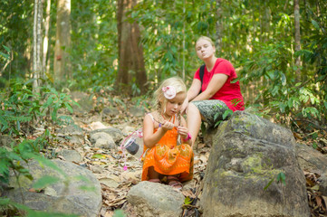 Mother and daughter seat on stones rest on break at hiking trail