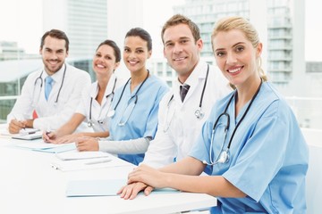 Male and female doctors sitting in row