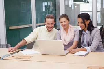 Three happy businessmen working together on a laptop