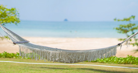 Empty hammock under palm trees at tropical beach resort with oce