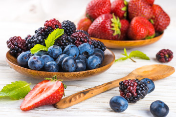Вunch of wild berries and mint on a wooden board