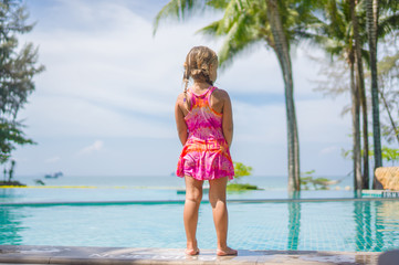 Adorable girl stay at side of swimming pool in tropical beach re