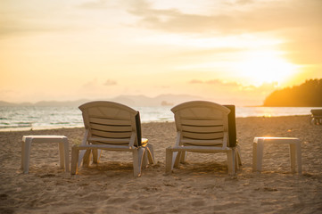 Two beach chairs at sunset near tropical ocean resort