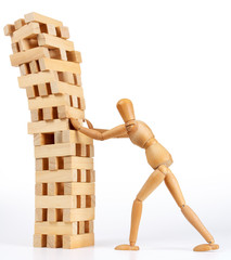 Wooden man figure pushing down tower