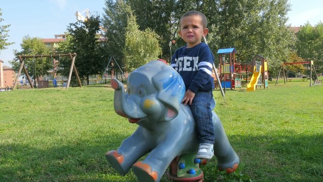 child on a rocking animal cries because he wants the pacifier