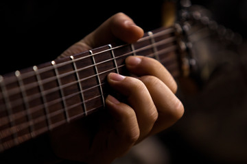 The hand of man playing guitar closeup