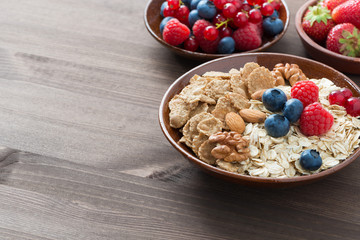 oatmeal, granola, nuts and berries on wooden background