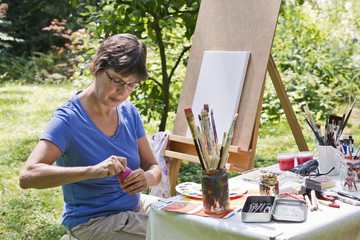 Frau malt ein Bild im Garten