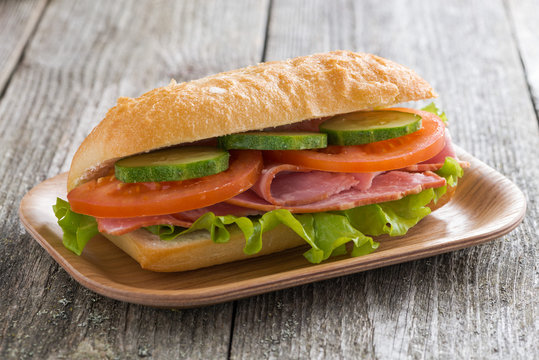 sandwich with ham and vegetables on wooden table, close-up