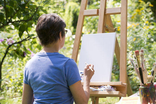 Frau malt ein Bild im Garten