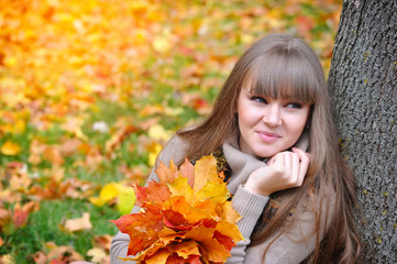 Portrait of beautiful young woman with autumn leaves