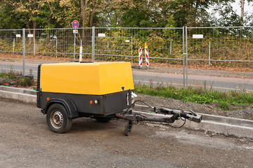 Strassenbauarbeiten und ein gelber fahrbarer Kompressor