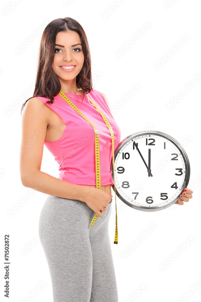 Wall mural Young woman holding a big wall clock