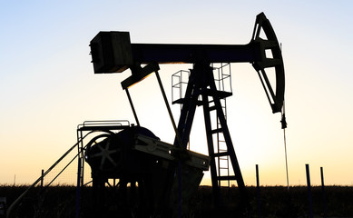 Operating oil and gas well profiled on sunset sky
