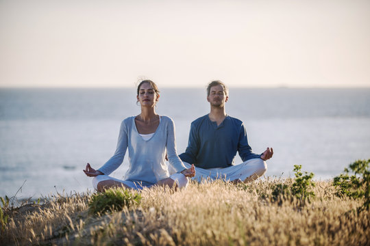 handsome couple practicing meditation exercises on the beach at