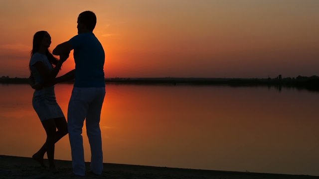 Couple in love dancing salsa at sunset
