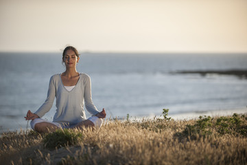 Naklejka na ściany i meble beautiful woman practicing meditation exercises on the beach at
