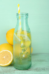Tasty cool beverage with lemon and thyme, on wooden background