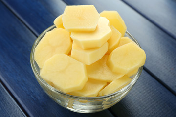 Raw peeled and sliced potatoes in glass bowl