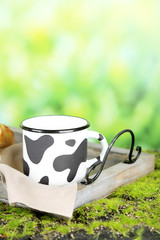 Mug of tasty milk on nature background